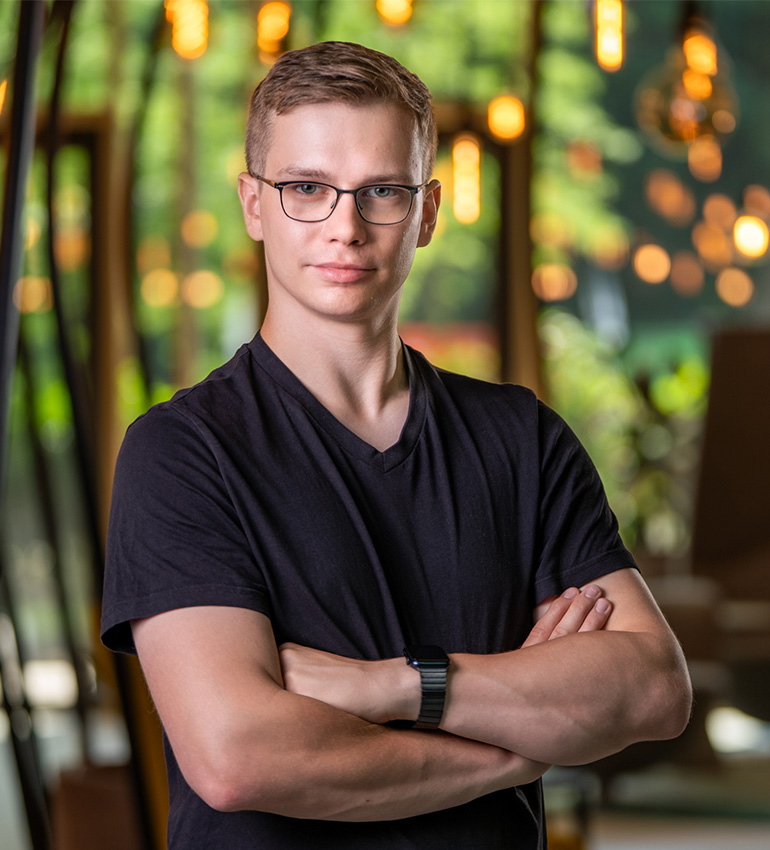 Cedric Rust: blonder, junger Mann mit Brille in schwarzem T-Shirt mit verschränkten Armen